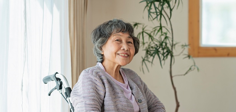Senior woman sitting in a wheelchair and happily gazing to the side