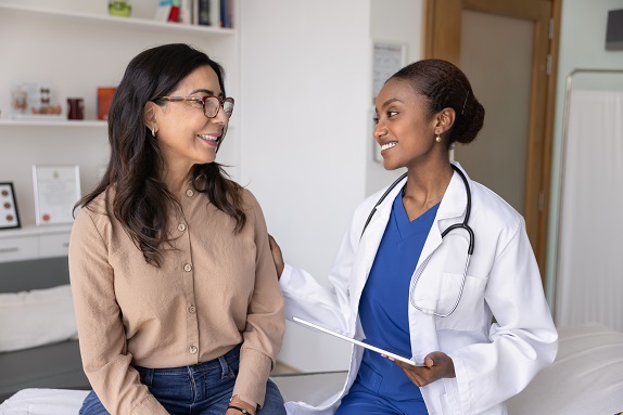 Young doctor in medical room with older patient happily showing results on clipboard