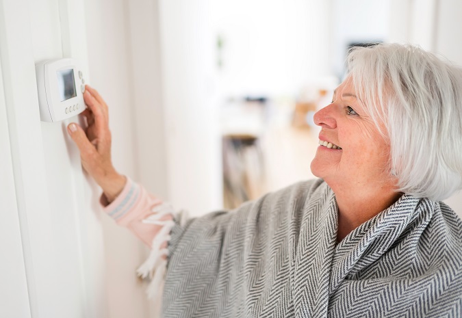 Woman smiling adjusting thermostat